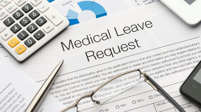 A medical leave request form with glasses, a calculator, and a pen.