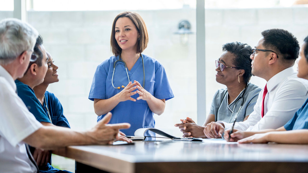 A nurse is talking to a group of people around a table.