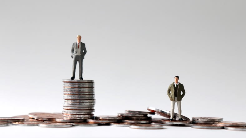 Two business men standing on top of a stack of coins.