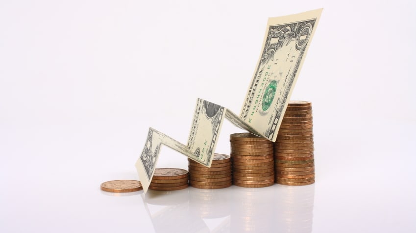 A stack of coins with a dollar bill in the middle.