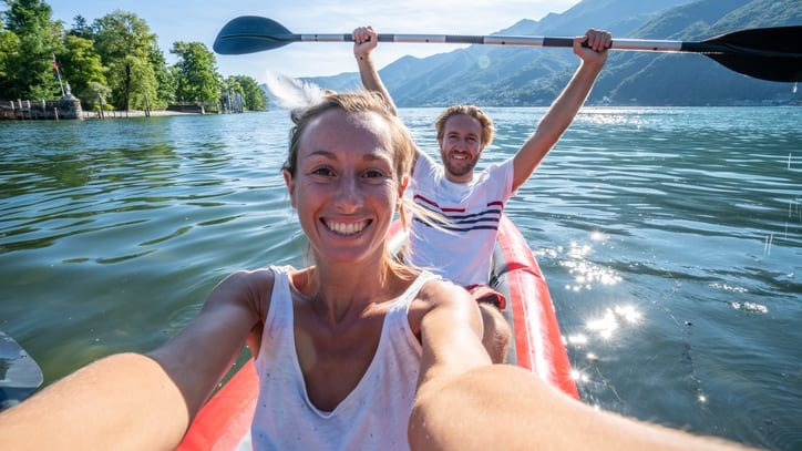 Two people taking a selfie in a kayak on a lake.