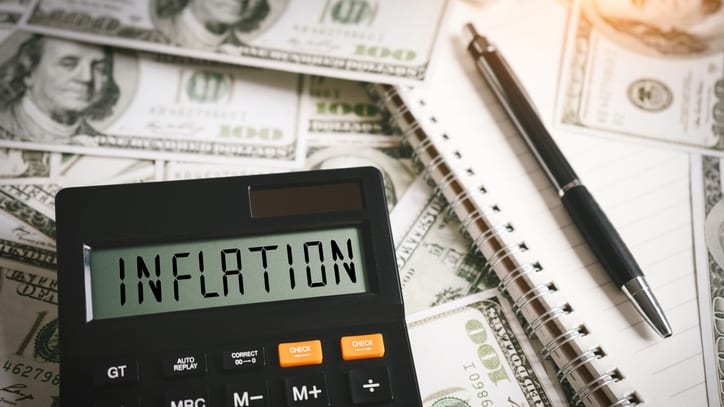 A calculator with the word inflation sitting on top of a pile of money.