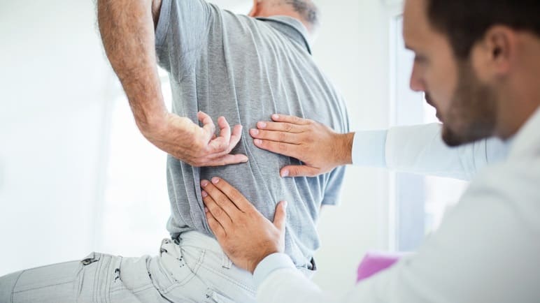 A man is having his back examined by a doctor.