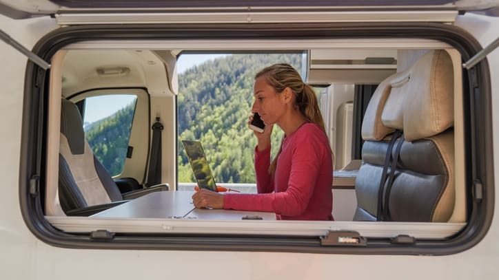 A woman is sitting in the back seat of an rv talking on the phone.