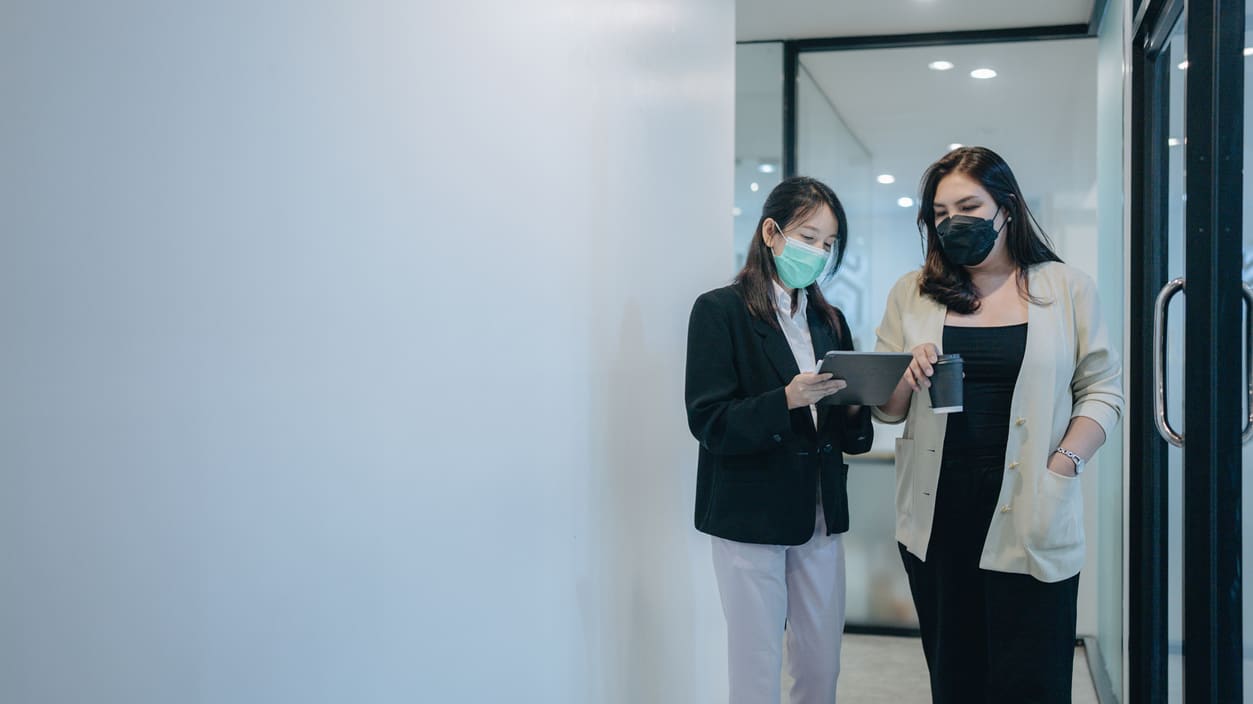 Two asian women wearing face masks in an office.