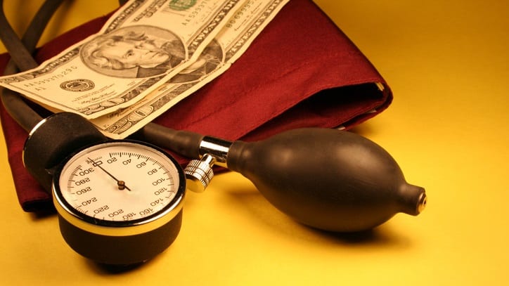 A stethoscope and money on a yellow background.