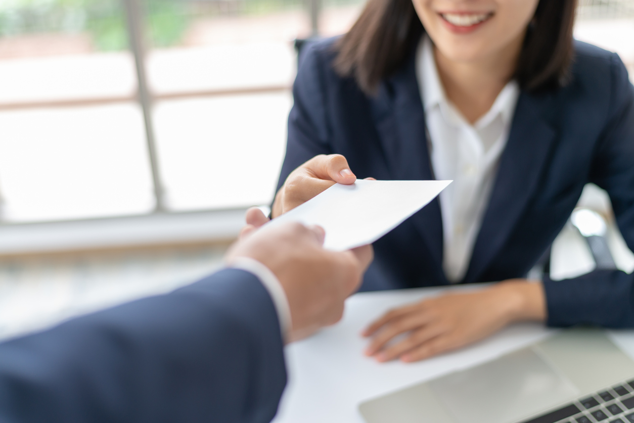 Woman receiving a bonus in envelope from manager at the office