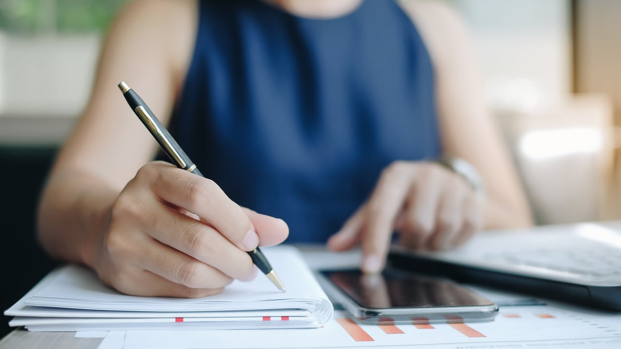 A woman is writing on a piece of paper with a pen.