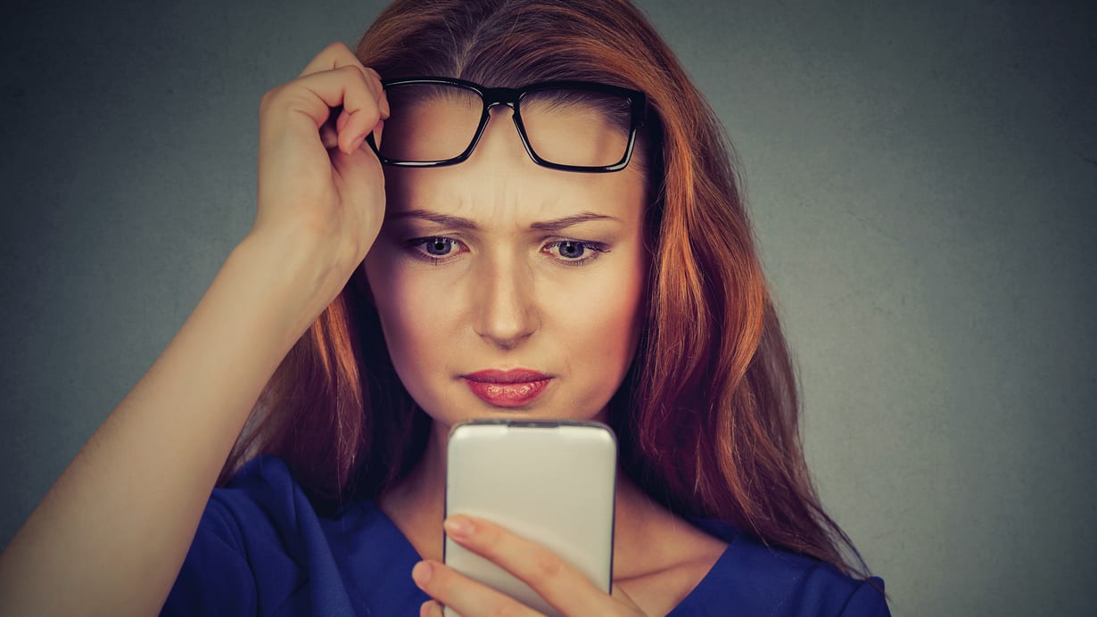 A woman with glasses looking at her phone.