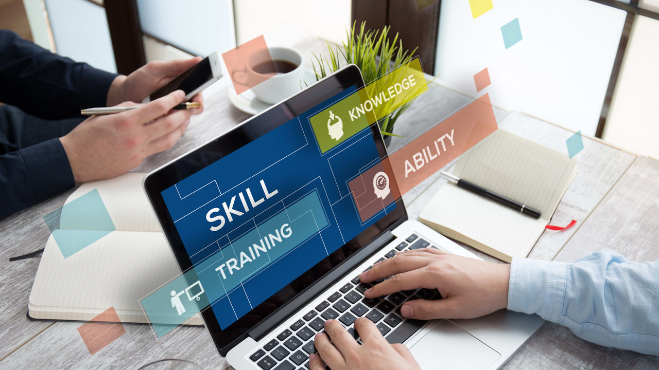 Two people working on a laptop with a skill training sign on it.