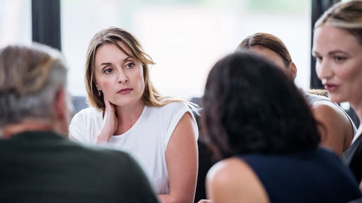 A group of people sitting around a table in a meeting.