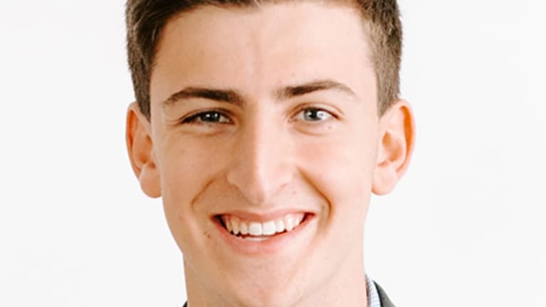 A young man smiling in a suit and tie.