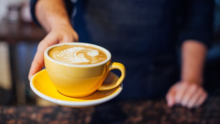 A barista is holding a cup of coffee.