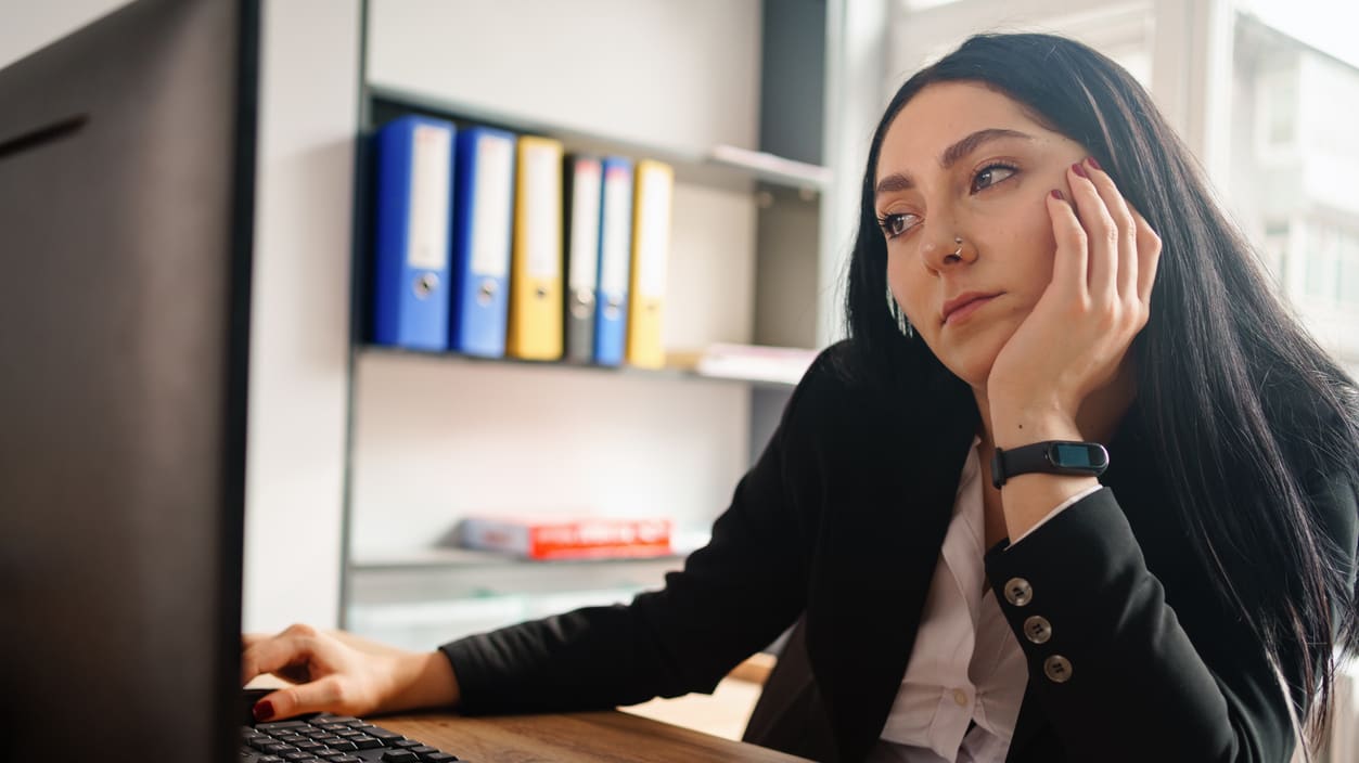 A woman sitting at a desk looking at a computer screen.