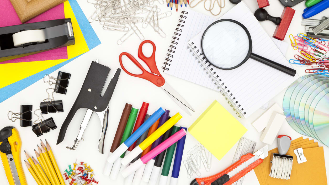 Office supplies arranged on a table with a magnifying glass.