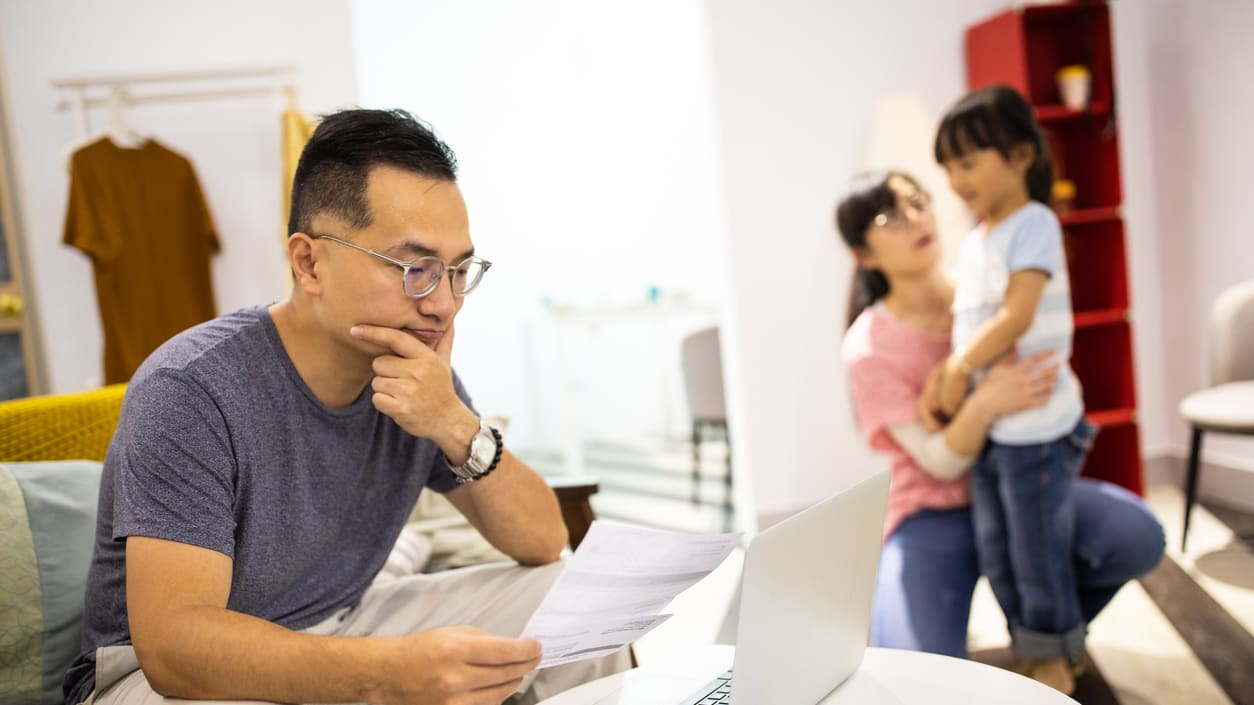 A man and woman sitting on a couch with a laptop in front of them.