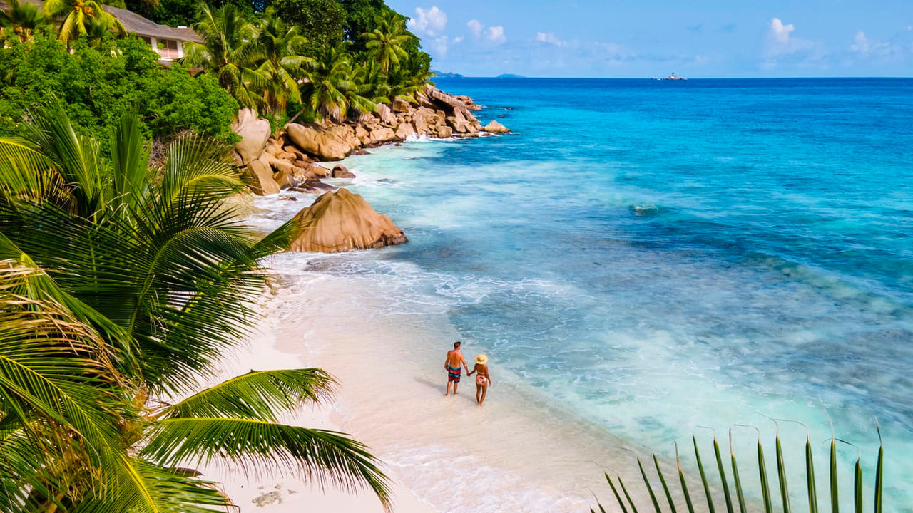 Two people walking on a beach near the ocean.