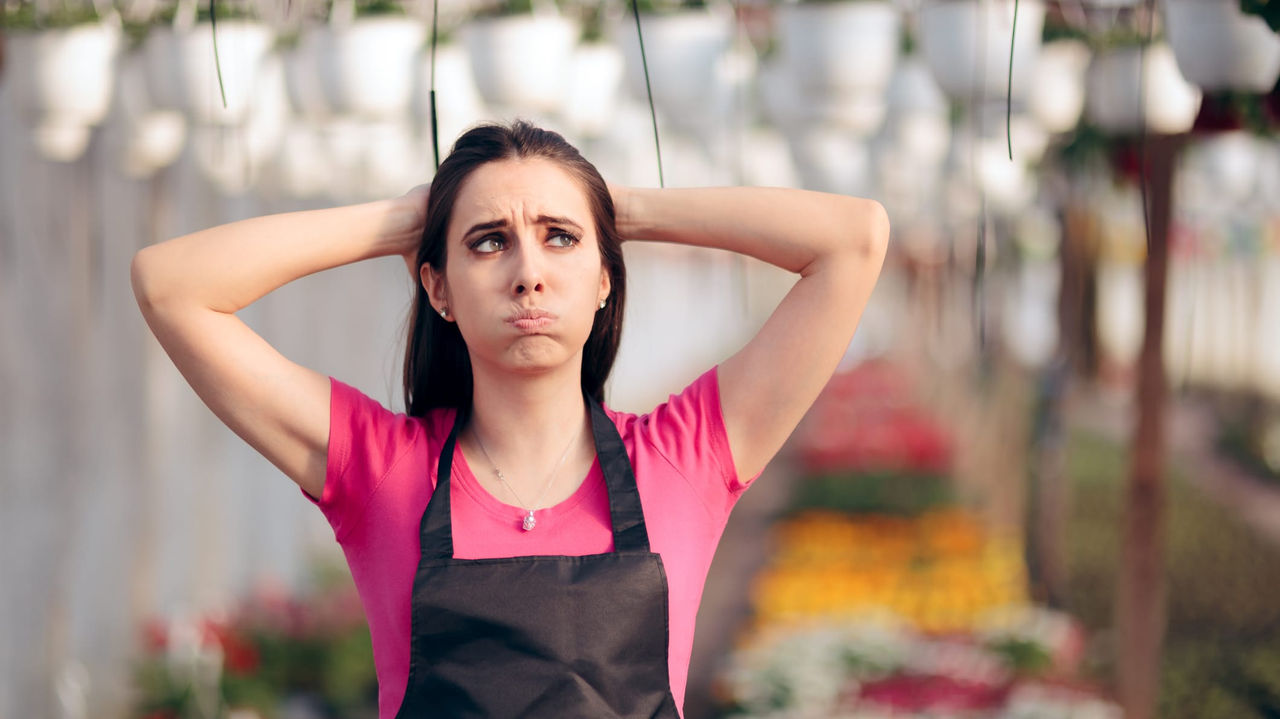 A woman in an apron standing in a greenhouse.