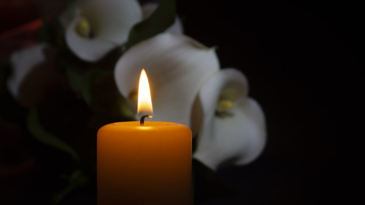 Calla lilies and a candle on a dark background.