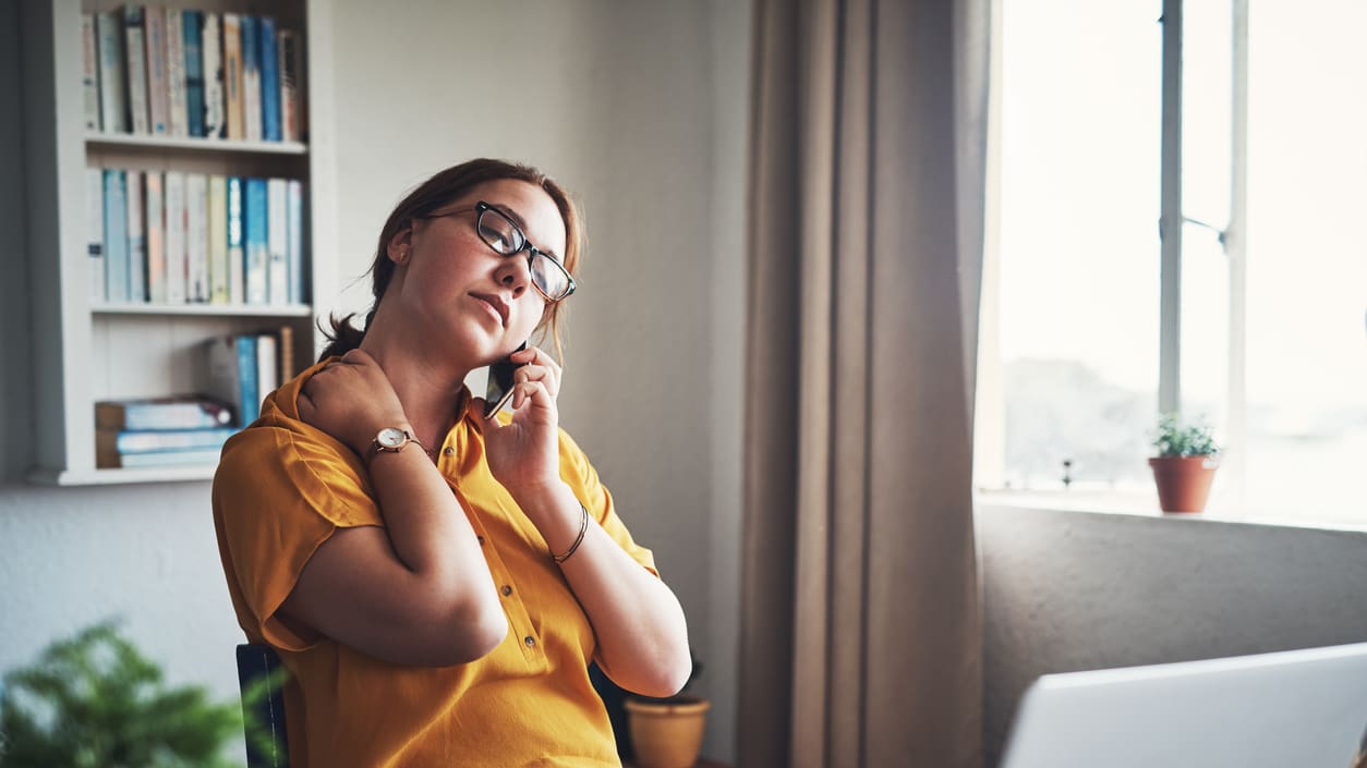 A woman talking on the phone while sitting in front of a window.