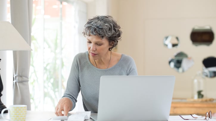 A woman is working on her laptop at home.