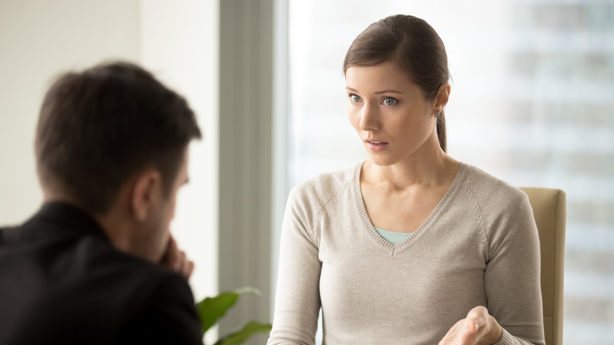 A woman is talking to a man in an office.