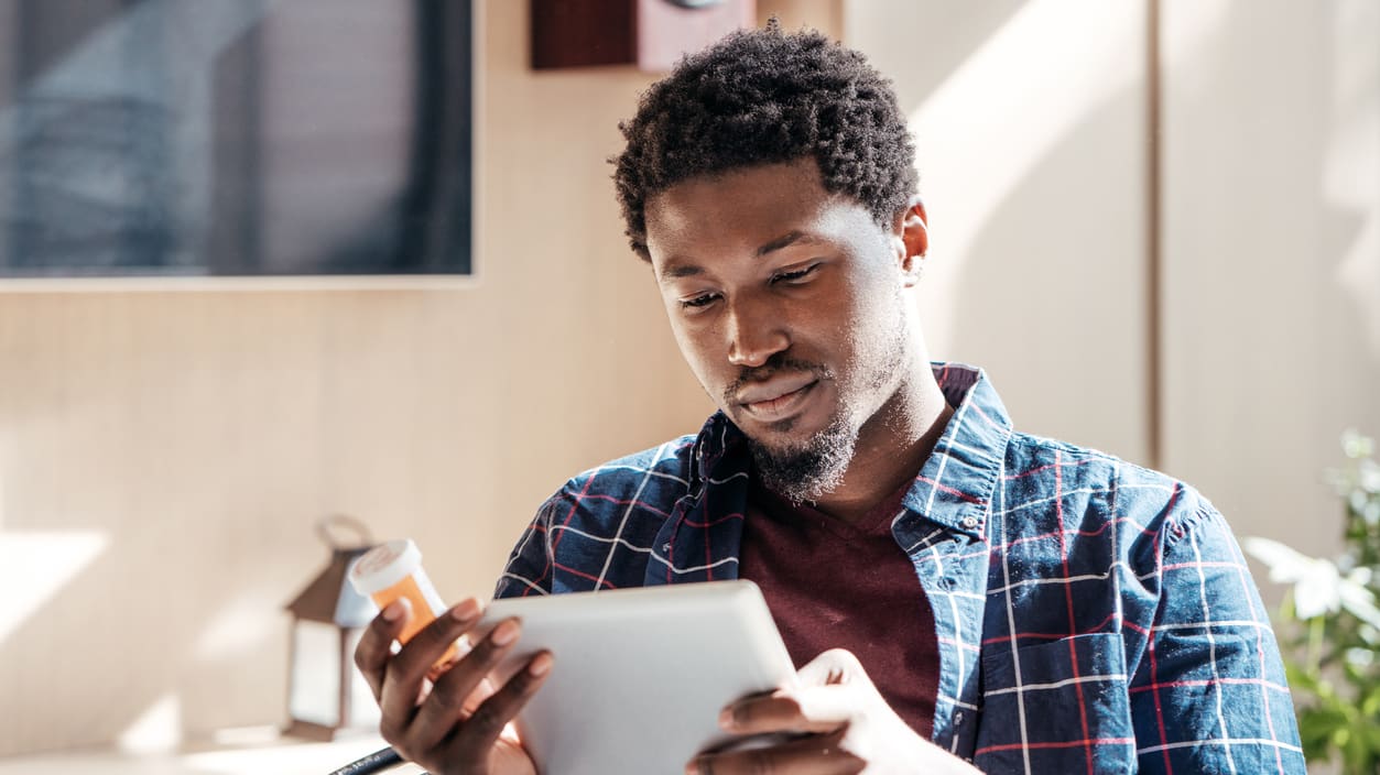 A man is using a tablet while sitting in front of a television.