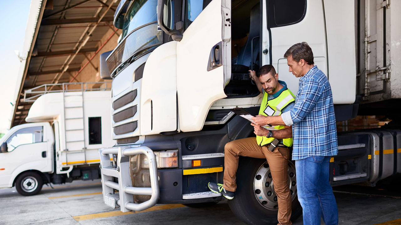 Two men standing next to a semi truck.