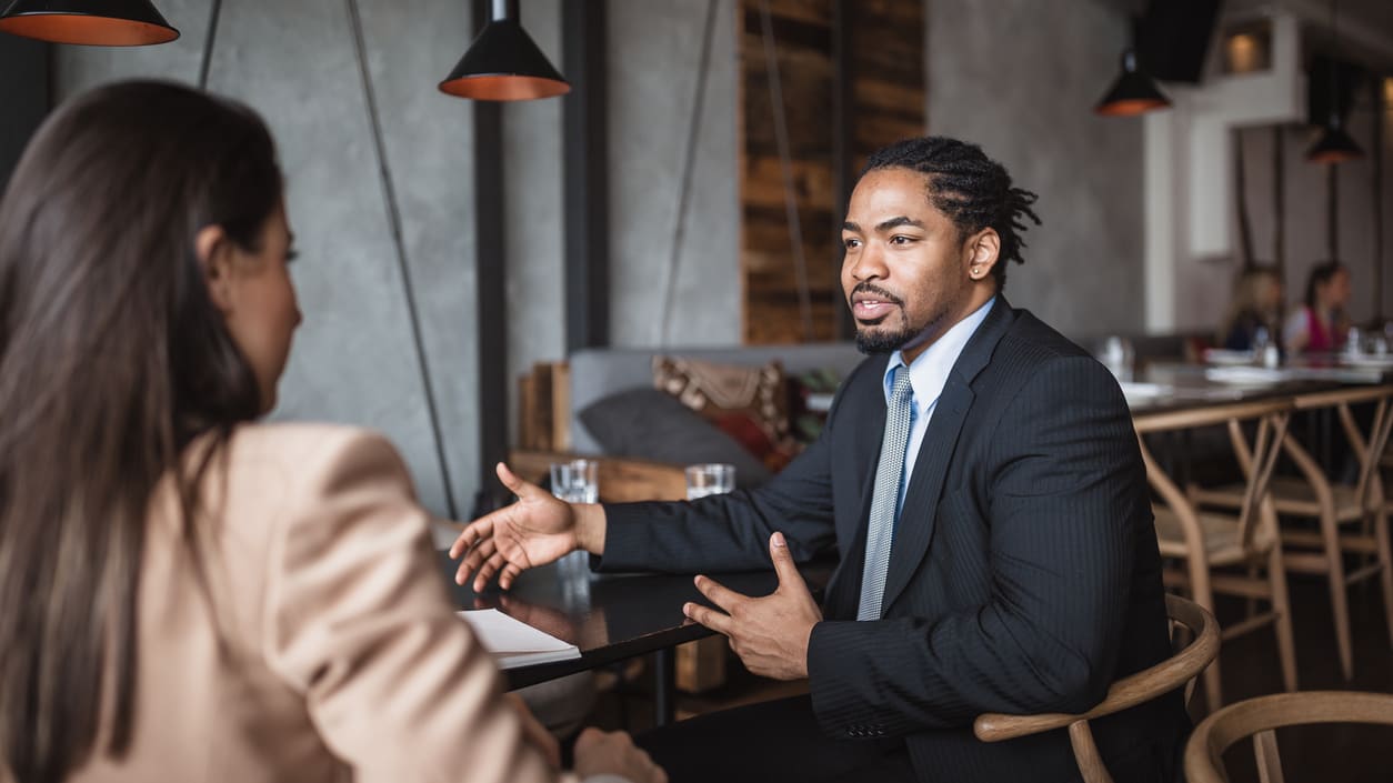 Two business people talking at a table in a restaurant.