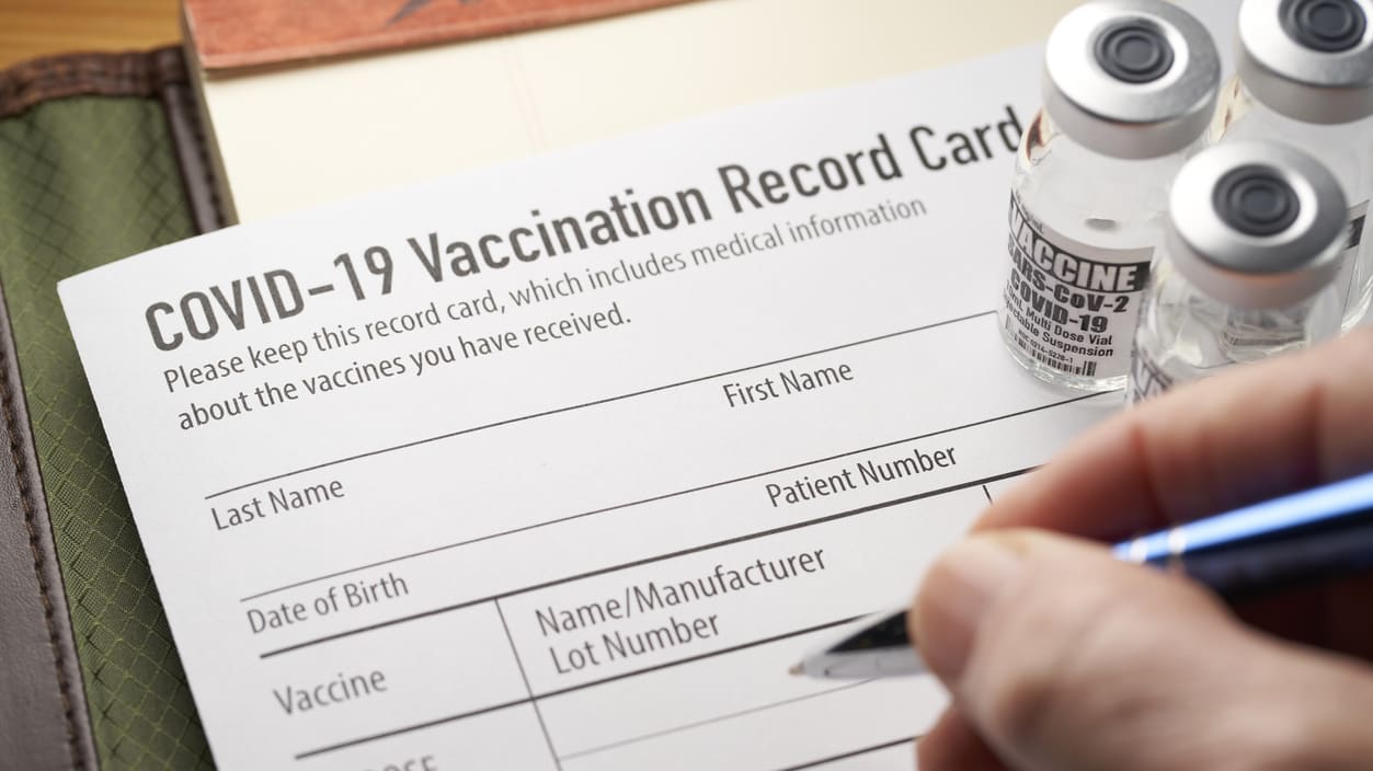A person filling out a covidii vaccination record card.