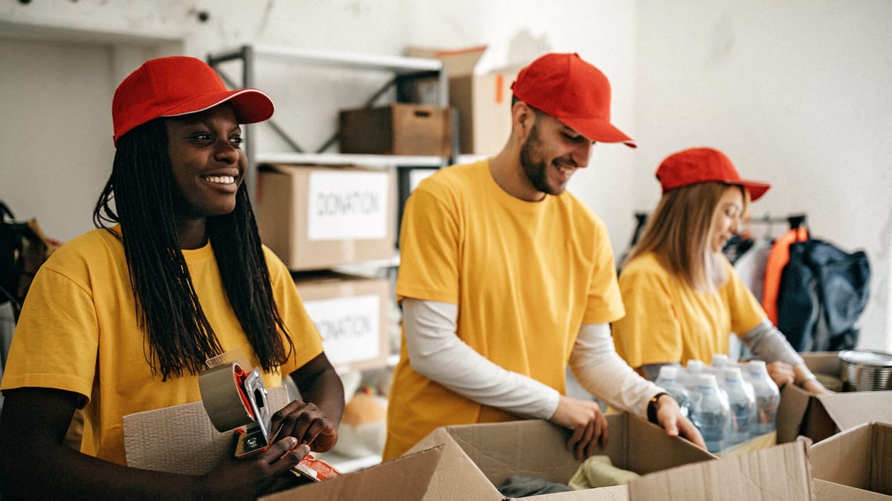 Three people in yellow hats working in a warehouse.