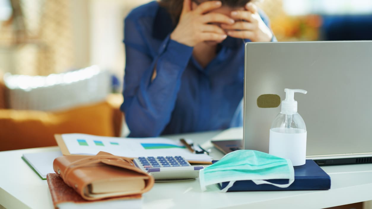 A woman with a face mask covering her face in front of a laptop.