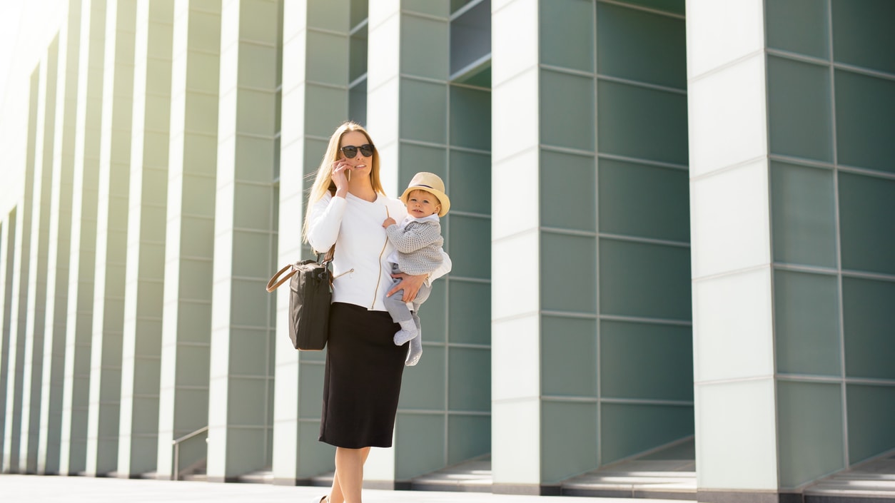 A woman is walking with a baby in her arms.