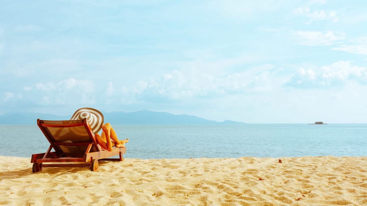A woman relaxes on a beach chair in front of the ocean.