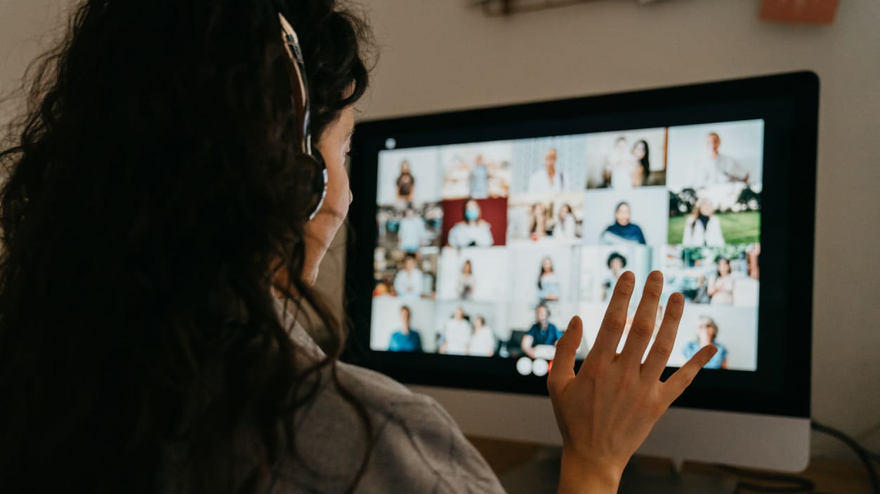 A woman is looking at a video on a computer screen.