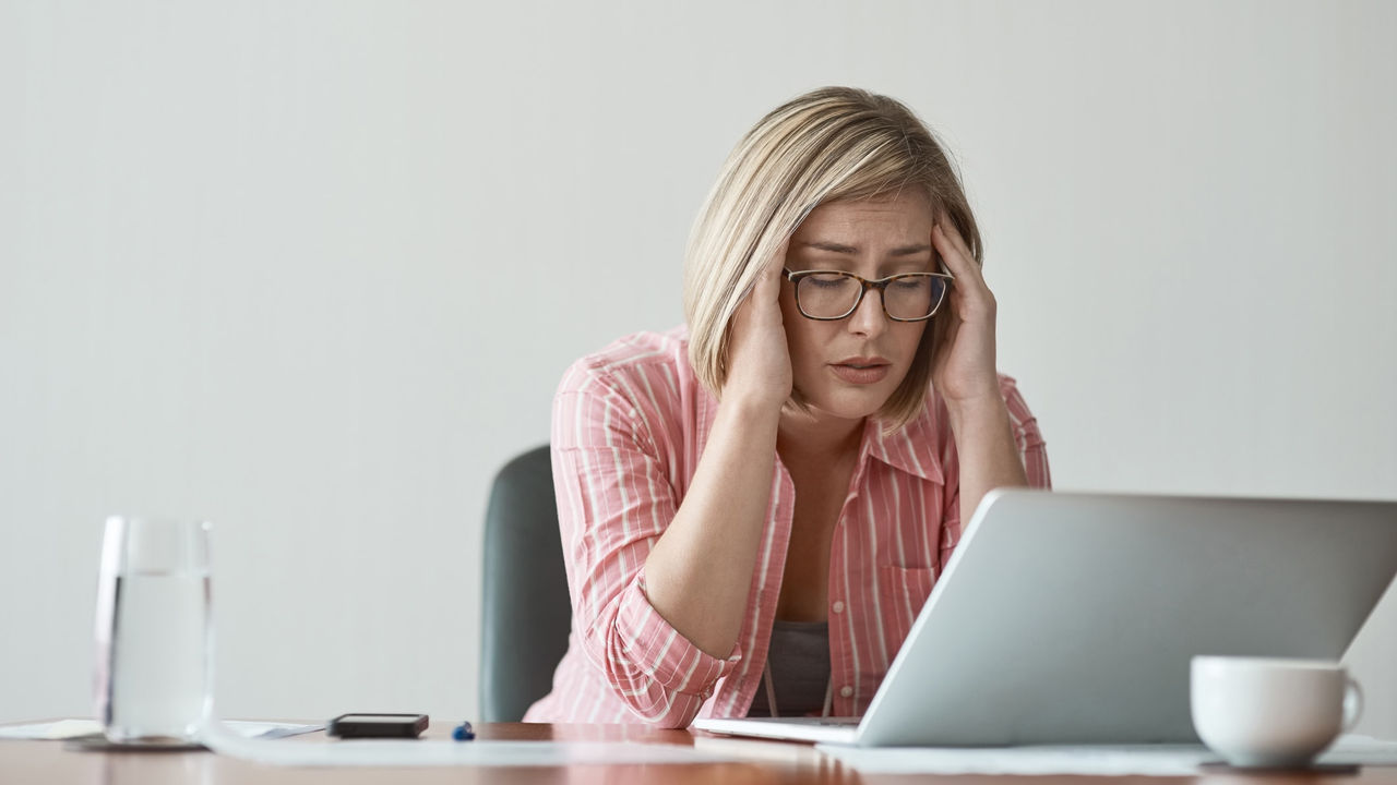 A woman is sitting at a desk with a laptop in front of her.