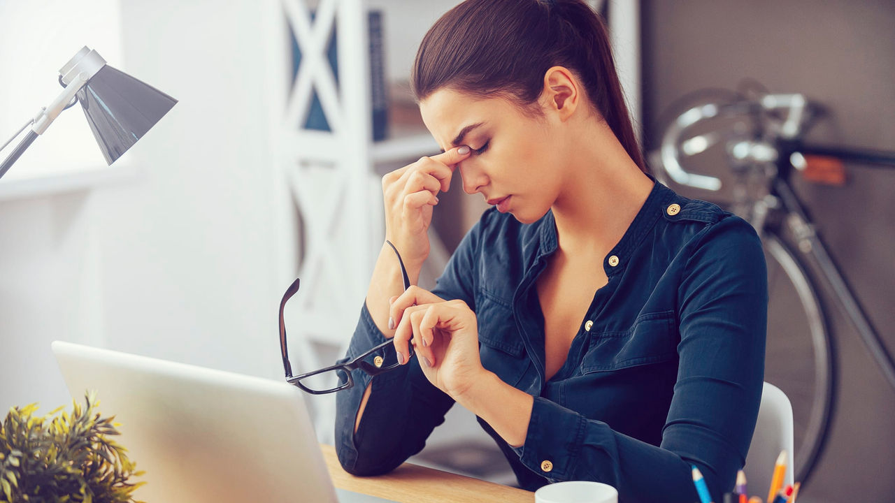 A woman is sitting at a desk with a laptop.