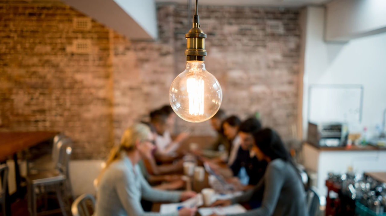 A group of people sitting around a table with a light bulb.