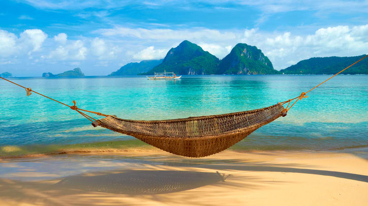 A hammock on a beach with turquoise water.