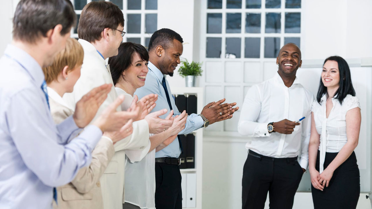 A group of business people clapping in an office.