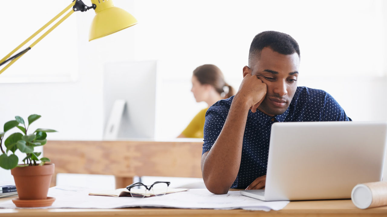 A man sitting at a desk looking at his laptop.