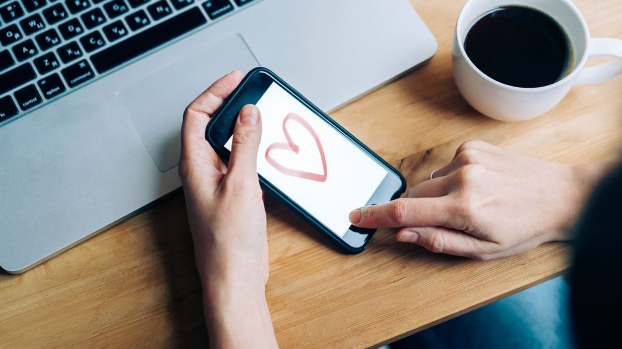 A woman using a smartphone with a heart drawn on it.