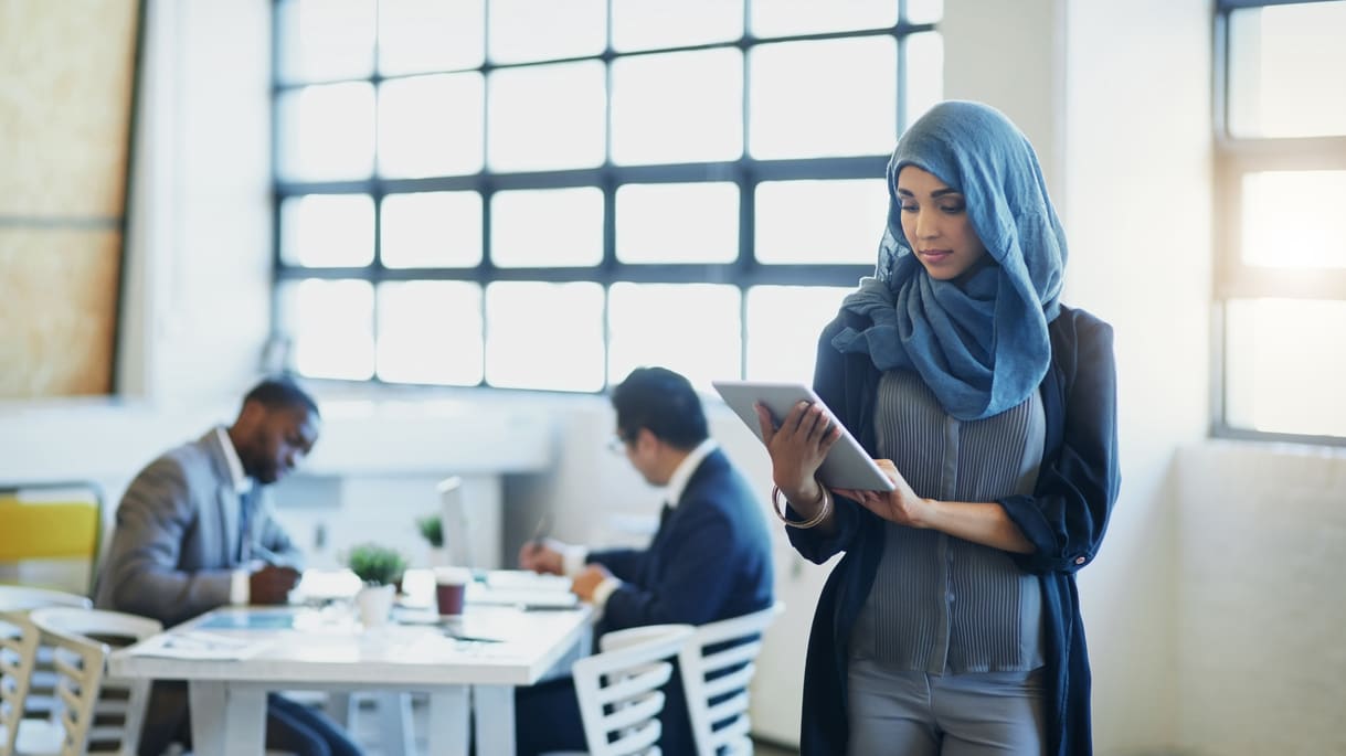 A muslim business woman using a tablet in an office.