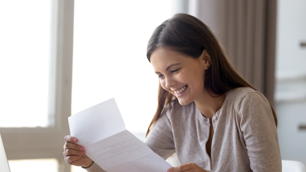 A woman is sitting at a desk and looking at a piece of paper.