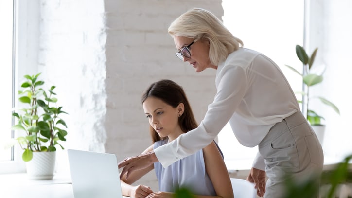 Two women working on a laptop in an office.