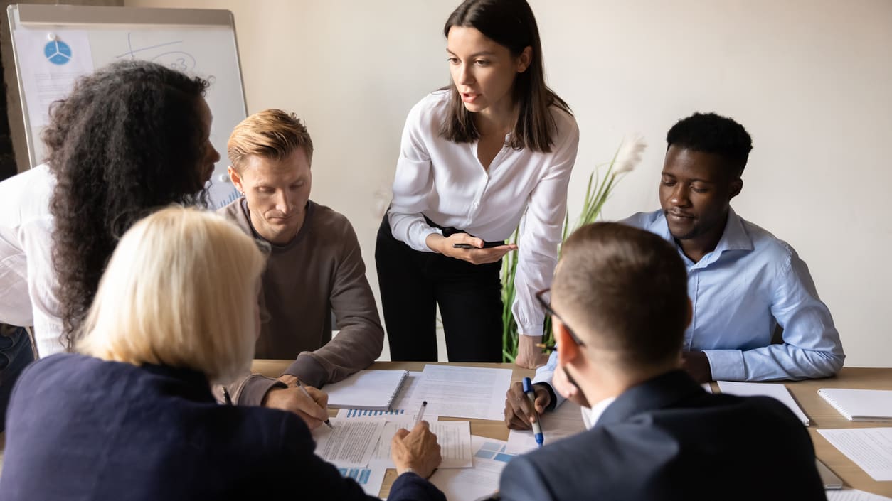 A group of people sitting around a table in a meeting.