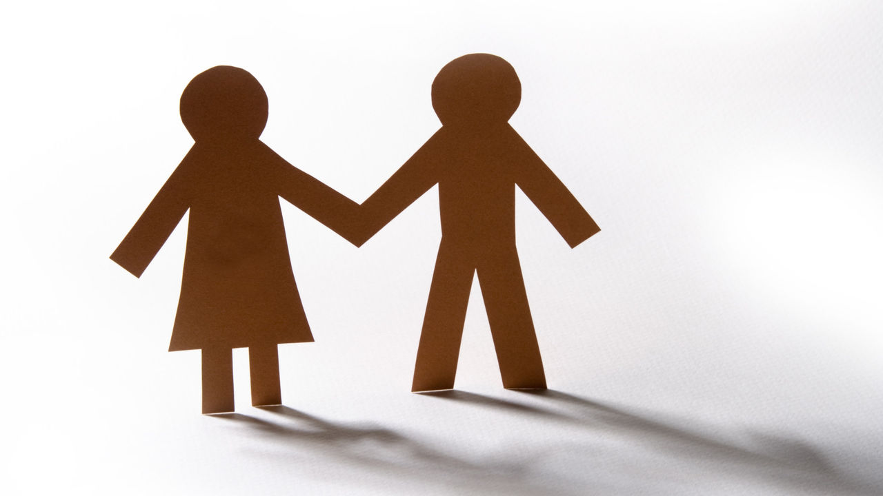 A couple holding hands in front of a white background.