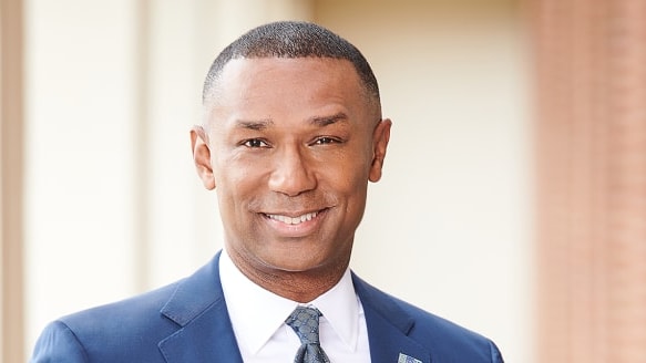 A man in a blue suit and tie smiling.