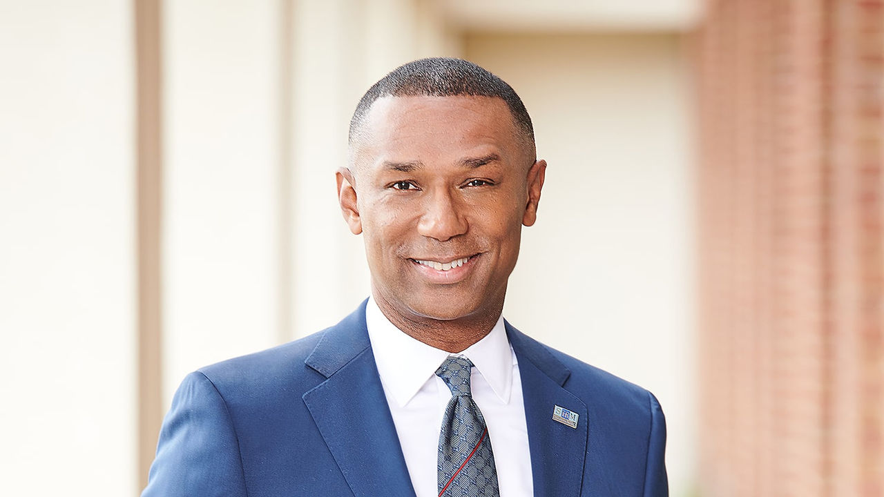 A man in a blue suit and tie smiling.