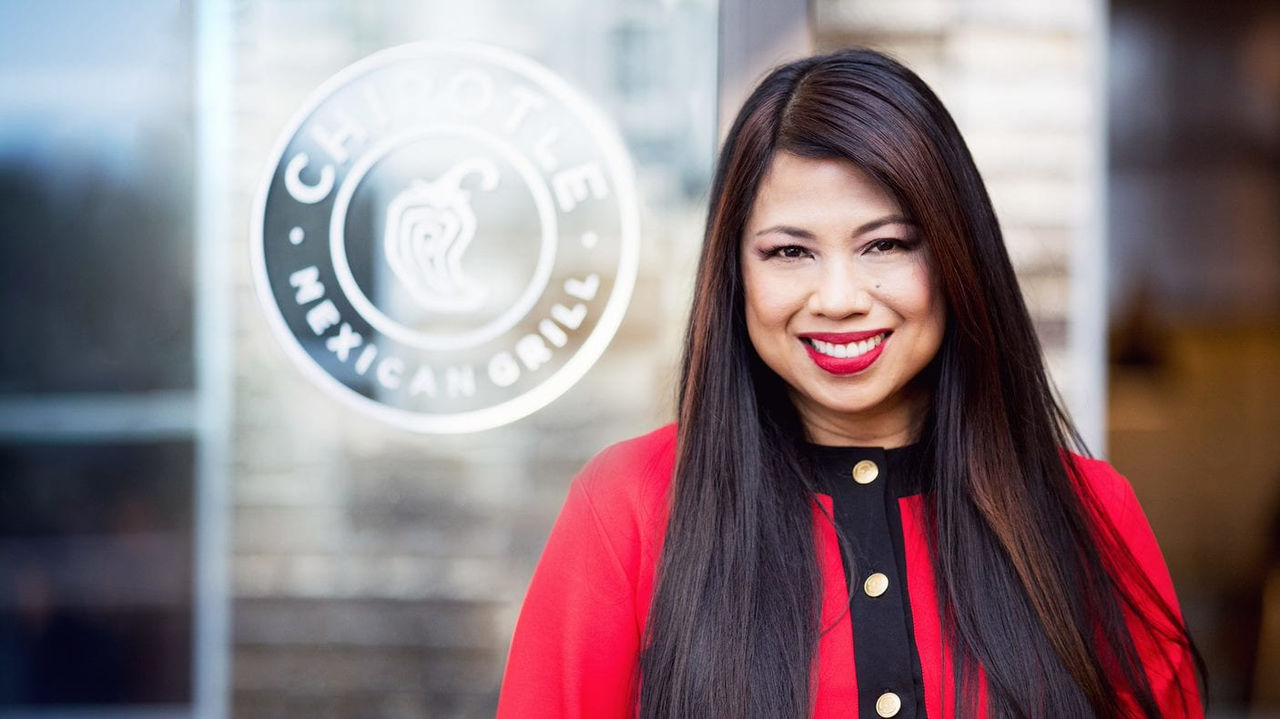 A woman in a red jacket standing in front of a building.